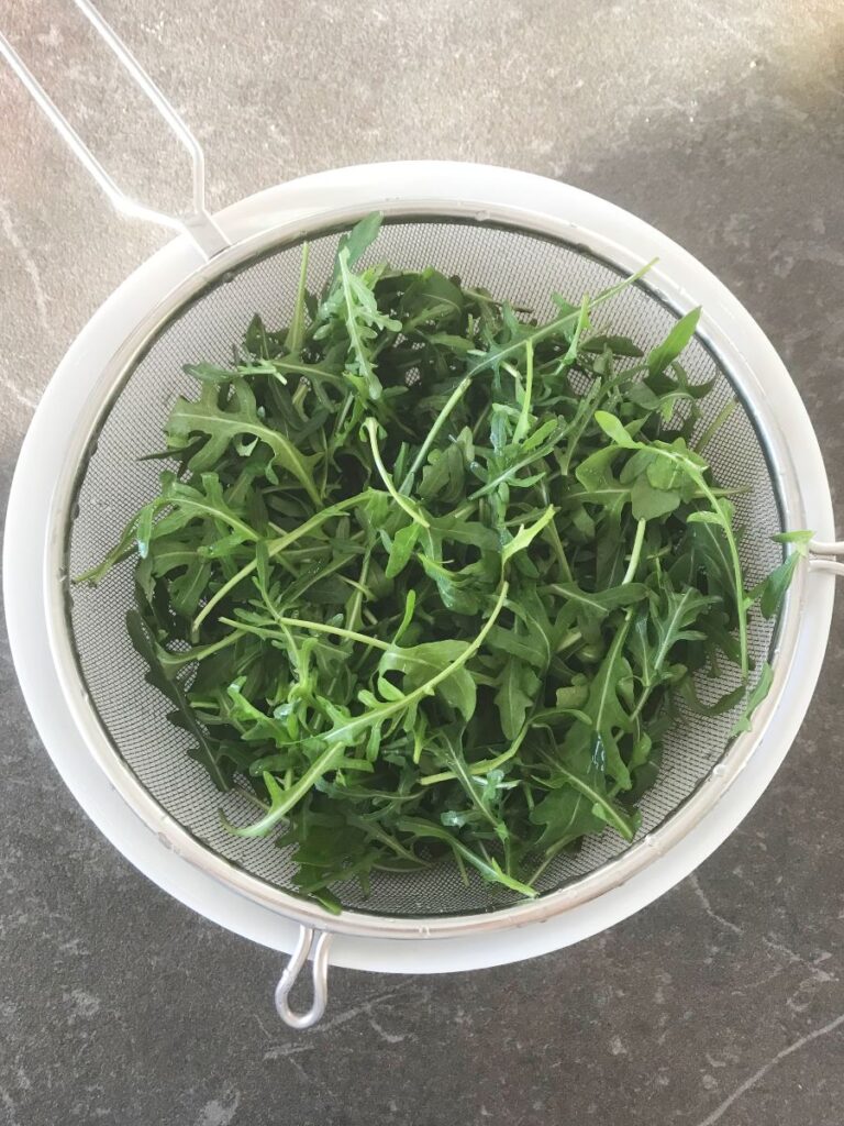 Washed arugula in a sieve