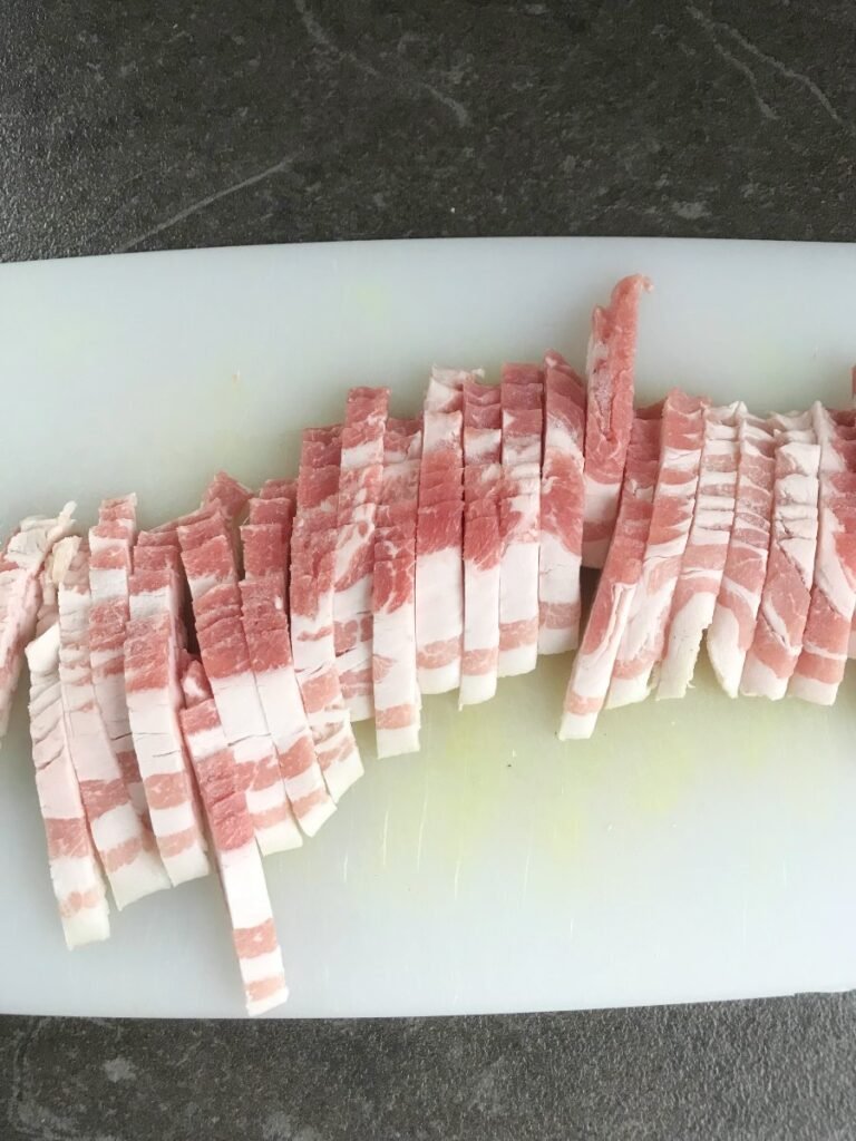 Bacon cut in strips on cutting board