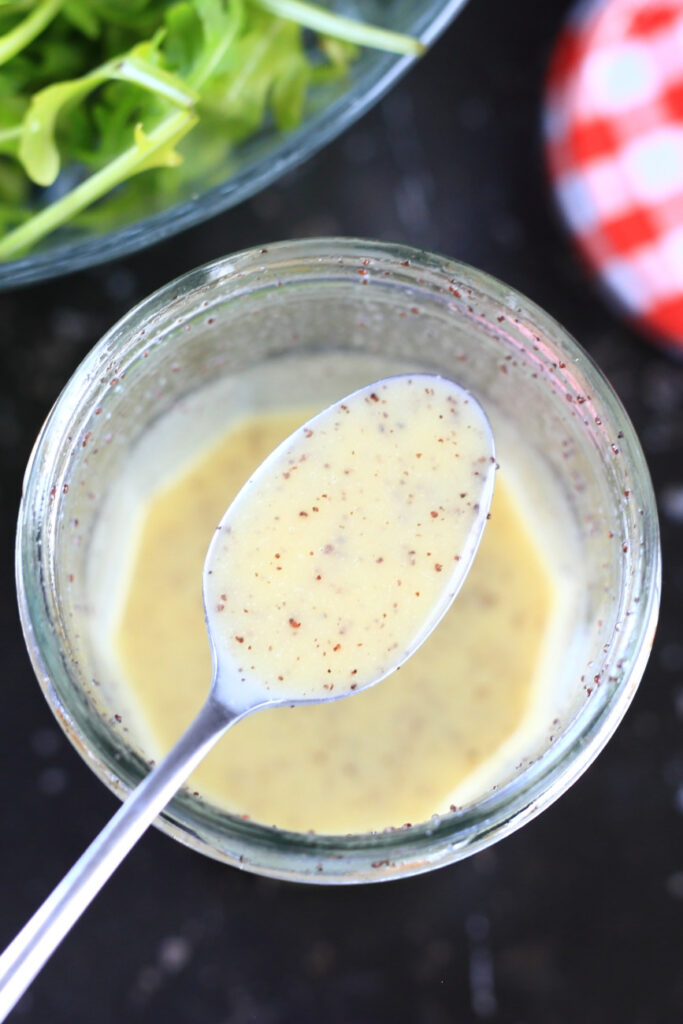 Poppy seed dressing with honey in a spoon over a jar