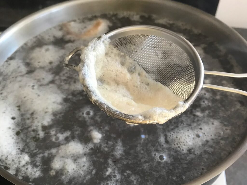 Beef bone broth skimming scum