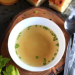 Beef bone broth served in a bowl with green onion