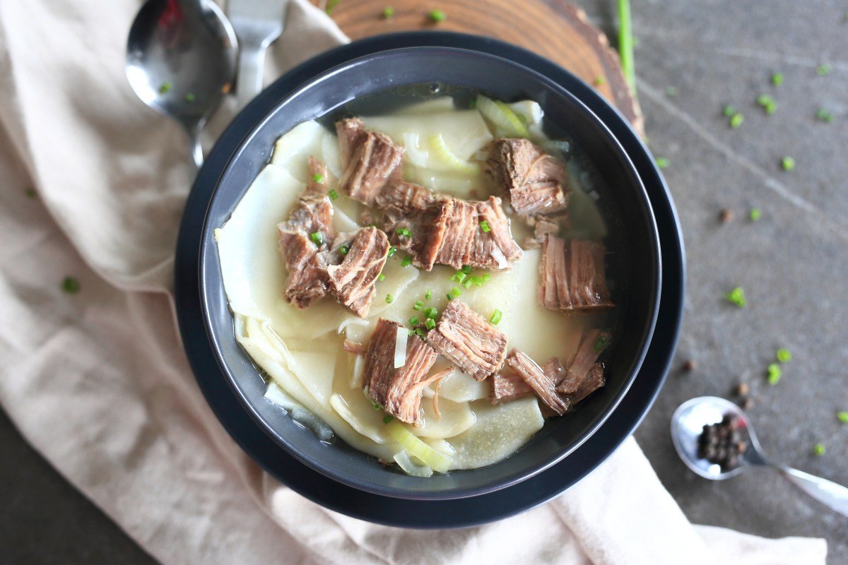 Beshbarmak served in a bowl with broth