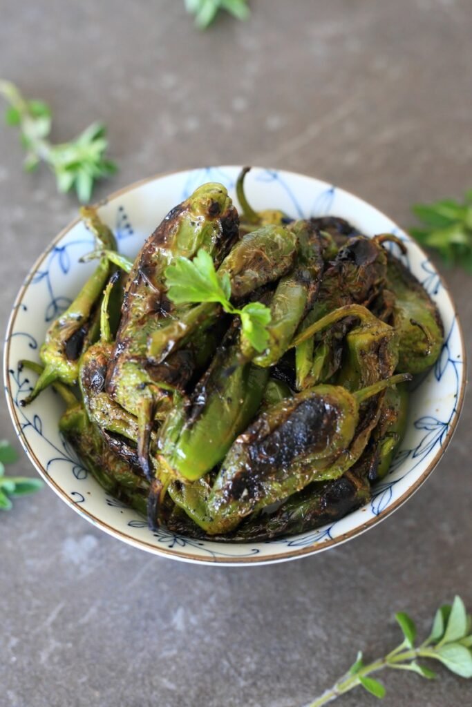 Grilled peppers served in a bowl and sprinkled with herbs